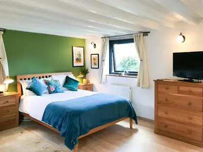 a bedroom with a bed and a flat screen tv at Little Fursdon Apartment in Liskeard