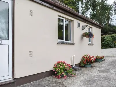 a white house with flowers on the side of it at Anneth Lowen in Perranwell