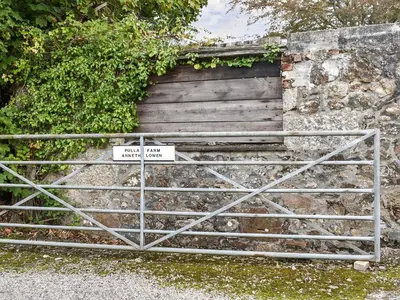 a gate with a sign in front of a stone wall at Anneth Lowen in Perranwell