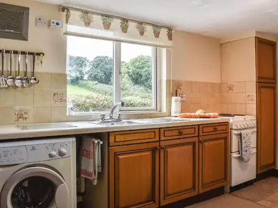 a kitchen with a washing machine and a window at Anneth Lowen in Perranwell