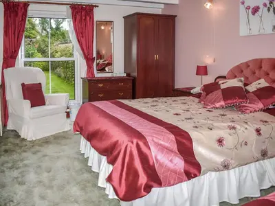 a bedroom with a bed and a chair and a window at Anneth Lowen in Perranwell