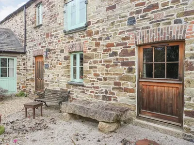 a brick building with a bench in front of it at Turneys Cottage - Uk42115 in Bodmin