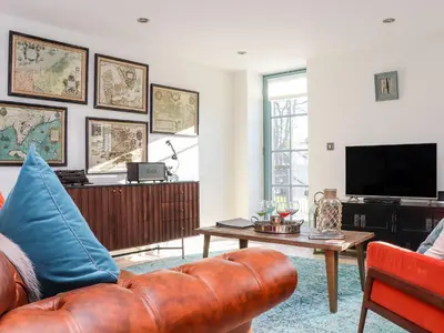 a living room with a brown leather couch and a tv at The Old Smokehouse in St Austell
