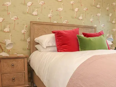 a bed with red and green pillows and a wall with flamingos at The Old Smokehouse in St Austell