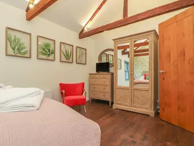 a bedroom with a bed and a red chair at The Old Smokehouse in St Austell