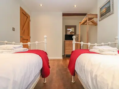 two beds in a bedroom with red blankets on them at The Old Smokehouse in St Austell