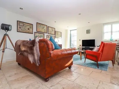 a living room with a brown leather couch and a red chair at The Old Smokehouse in St Austell