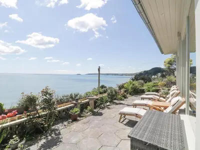 a patio with chairs and a view of the water at Raven Cottage in Torpoint