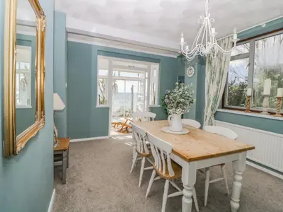 a dining room with blue walls and a wooden table and chairs at Raven Cottage in Torpoint
