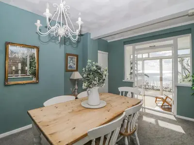 a dining room with a wooden table and chairs at Raven Cottage in Torpoint
