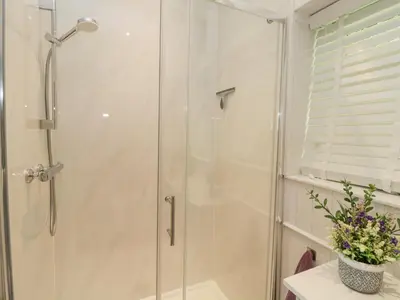 a shower with a glass door in a bathroom at Raven Cottage in Torpoint