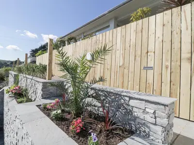 a garden with a fence and a retaining wall at Raven Cottage in Torpoint