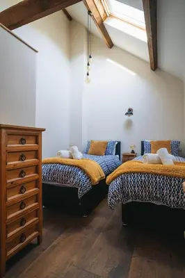 a room with two beds and a dresser in it at Swallows Nest at Widemouth Bay - 2 bedroom cottage in Bude