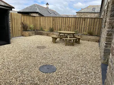 a patio with a picnic table and a fence at Swallows Nest at Widemouth Bay - 2 bedroom cottage in Bude