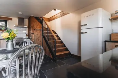 a kitchen with a staircase and a white refrigerator at Swallows Nest at Widemouth Bay - 2 bedroom cottage in Bude