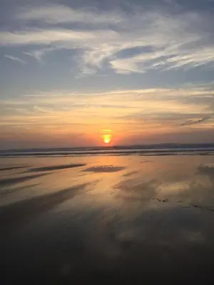 a sunset on the beach with the sun setting at Swallows Nest at Widemouth Bay - 2 bedroom cottage in Bude