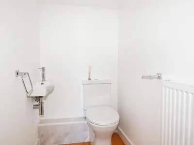 a white bathroom with a toilet and a sink at 6B The Mews in Padstow