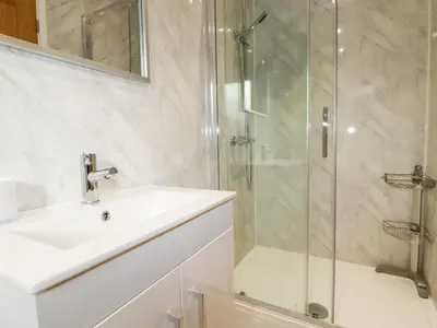 a bathroom with a sink and a glass shower at 6B The Mews in Padstow