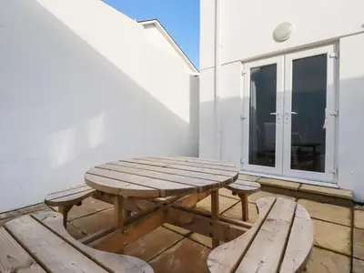 a wooden picnic table and two benches on a patio at 6A The Mews in Padstow