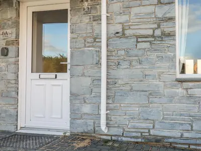 a white door on a stone house with a window at 6A The Mews in Padstow