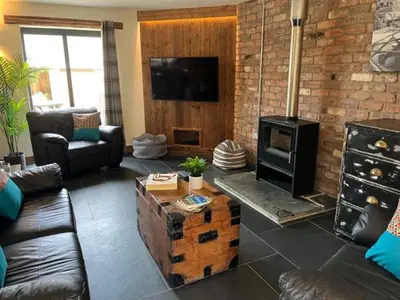 a living room with a couch and a fireplace at The Stable at Widemouth Bay - 2 bedroom cottage in Poundstock