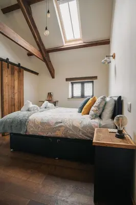 a bedroom with a large bed and a window at The Stable at Widemouth Bay - 2 bedroom cottage in Poundstock