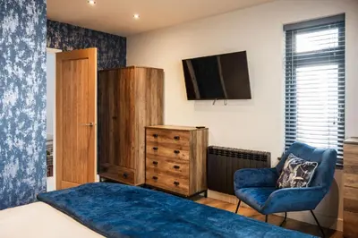 a bedroom with a bed and a chair and a television at Porthleven View in Porthleven