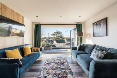 a living room with blue couches and a large window at Porthleven View in Porthleven