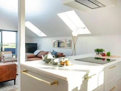 a kitchen with a white counter top and a living room at Rosefern in Tintagel