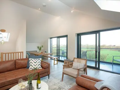 a living room with a couch and chairs and windows at Rosefern in Tintagel