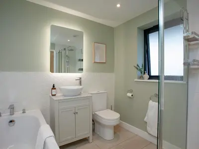 a bathroom with a sink toilet and a mirror at Rosefern in Tintagel