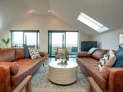 a living room with brown leather couches and a tv at Rosefern in Tintagel
