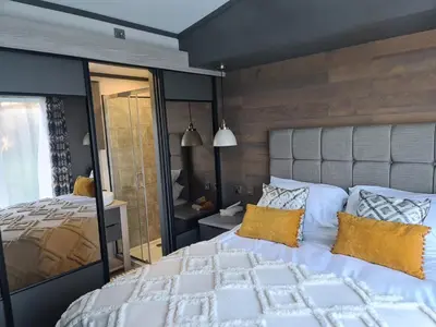 a bedroom with a large white bed with yellow pillows at Mawgan Pads Lazy Days Lodge in Mawgan Porth