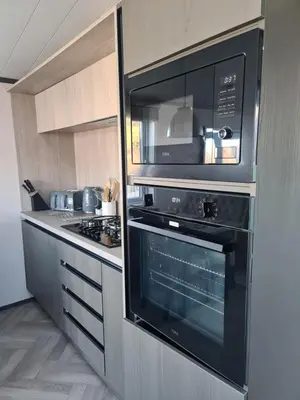 a kitchen with a black microwave and a stove at Mawgan Pads Lazy Days Lodge in Mawgan Porth
