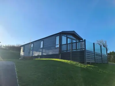 a house on top of a grassy hill at Mawgan Pads Lazy Days Lodge in Mawgan Porth