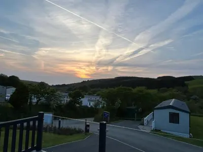 a view of a road with a house and a sunset at Mawgan Pads Lazy Days Lodge in Mawgan Porth