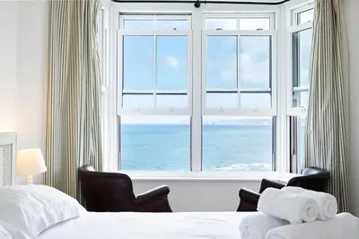 a bedroom with a large window overlooking the ocean at Bellevue, Port Isaac Bay Holidays in Port Isaac