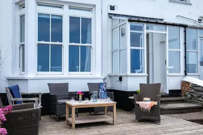 a patio with chairs and a table in front of a building at Bellevue, Port Isaac Bay Holidays in Port Isaac