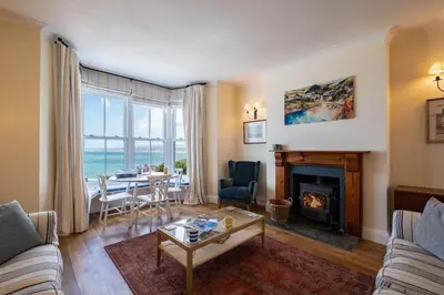 a living room with a fireplace and a table at Bellevue, Port Isaac Bay Holidays in Port Isaac