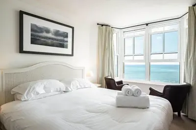 a bedroom with a white bed with two towels on it at Bellevue, Port Isaac Bay Holidays in Port Isaac