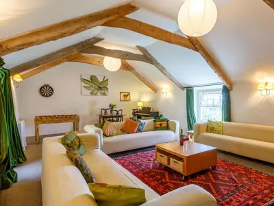 a living room with white couches and a table at Aaron's Cottage in Bodmin