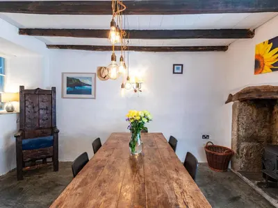 a dining room with a wooden table and a vase of flowers at Aaron's Cottage in Bodmin