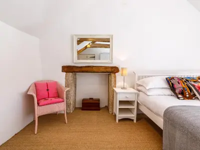 a bedroom with a bed and a chair and a mirror at Aaron's Cottage in Bodmin