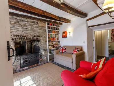 a living room with a red couch and a stone fireplace at Aaron's Cottage in Bodmin