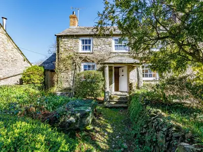 an old stone house with a white door at Aaron's Cottage in Bodmin