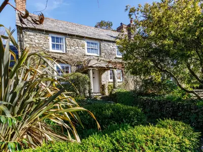 an old stone house with plants in front of it at Aaron's Cottage in Bodmin