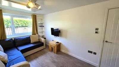a living room with a blue couch and a tv at 12 Wheal Ramoth in Perranporth