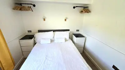 a small room with a bed with white sheets and pillows at 12 Wheal Ramoth in Perranporth