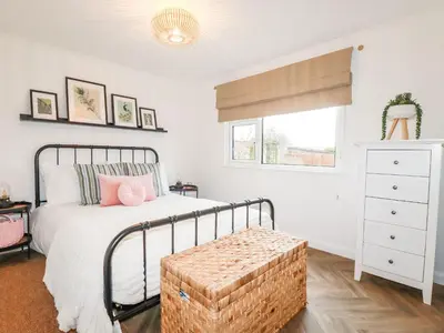 a bedroom with a bed with a wicker ottoman next to a window at Badgers Sett in Tintagel