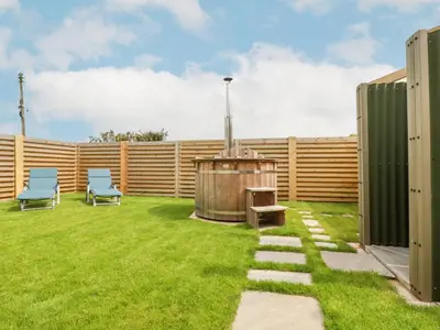 a garden with two chairs and a wooden fence at Badgers Sett in Tintagel